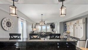 A modern kitchen with a large island, pendant lights, and a clock on the wall. - New Renovated Beachfront Unit-Boardwalk 881-Gulf Shores-Signature Properties (Gulf Shores)