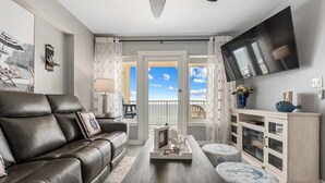 A modern living room with a leather sofa, a coffee table, and a TV mounted on the wall. - New Renovated Beachfront Unit-Boardwalk 881-Gulf Shores-Signature Properties (Gulf Shores)