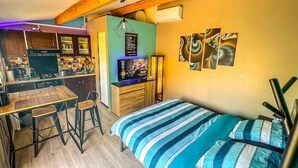 Ein kleines Zimmer mit Bett, einer Küchenzeile und einem Essbereich.