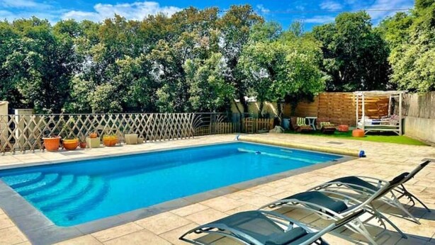 Ein rechteckiger Pool mit Holzterrasse und Liegestühlen.