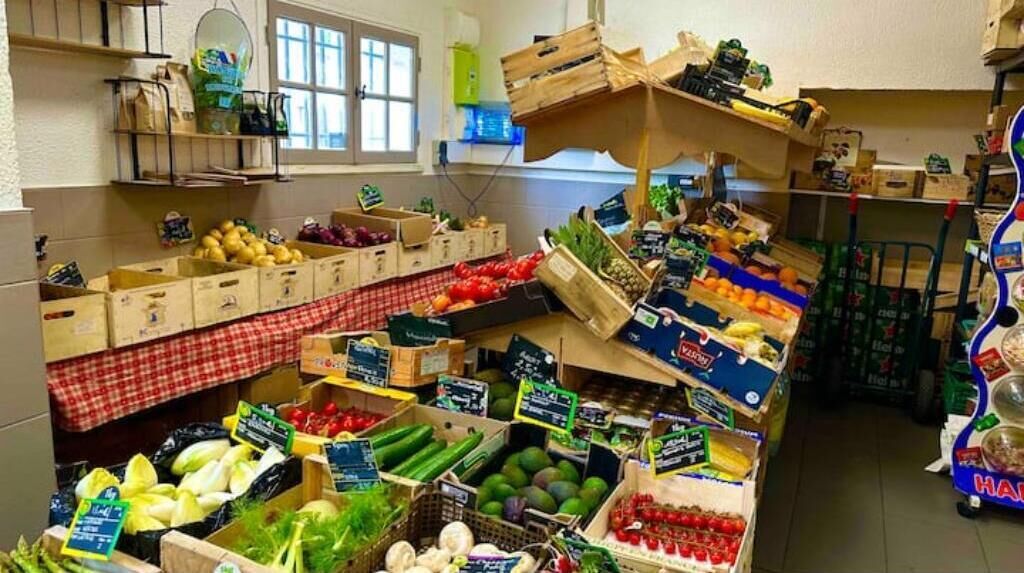 A market stall with various fruits and vegetables displayed in crates and bins.