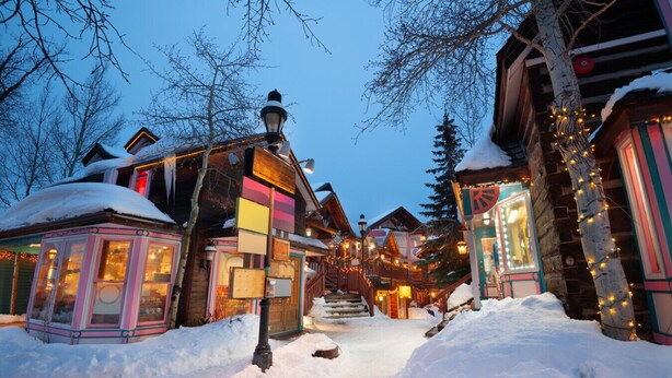Un pueblo cubierto de nieve con edificios de madera, una escalera visible y un farol.