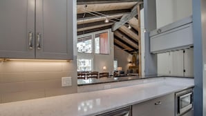 Cocina moderna con gabinetes grises, electrodomésticos de acero inoxidable y encimera de mármol.