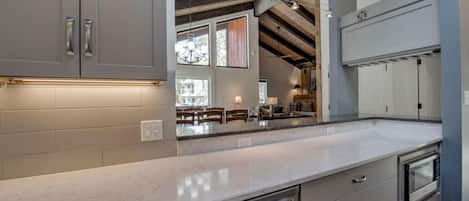 A modern kitchen with grey cabinets, stainless steel appliances, and a marble countertop.