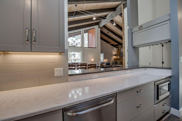 A modern kitchen with grey cabinets, stainless steel appliances, and a marble countertop. - Walk to Slopes & Main St | Modern 1BR Condo w/ Pool + Hot Tubs (Breckenridge)