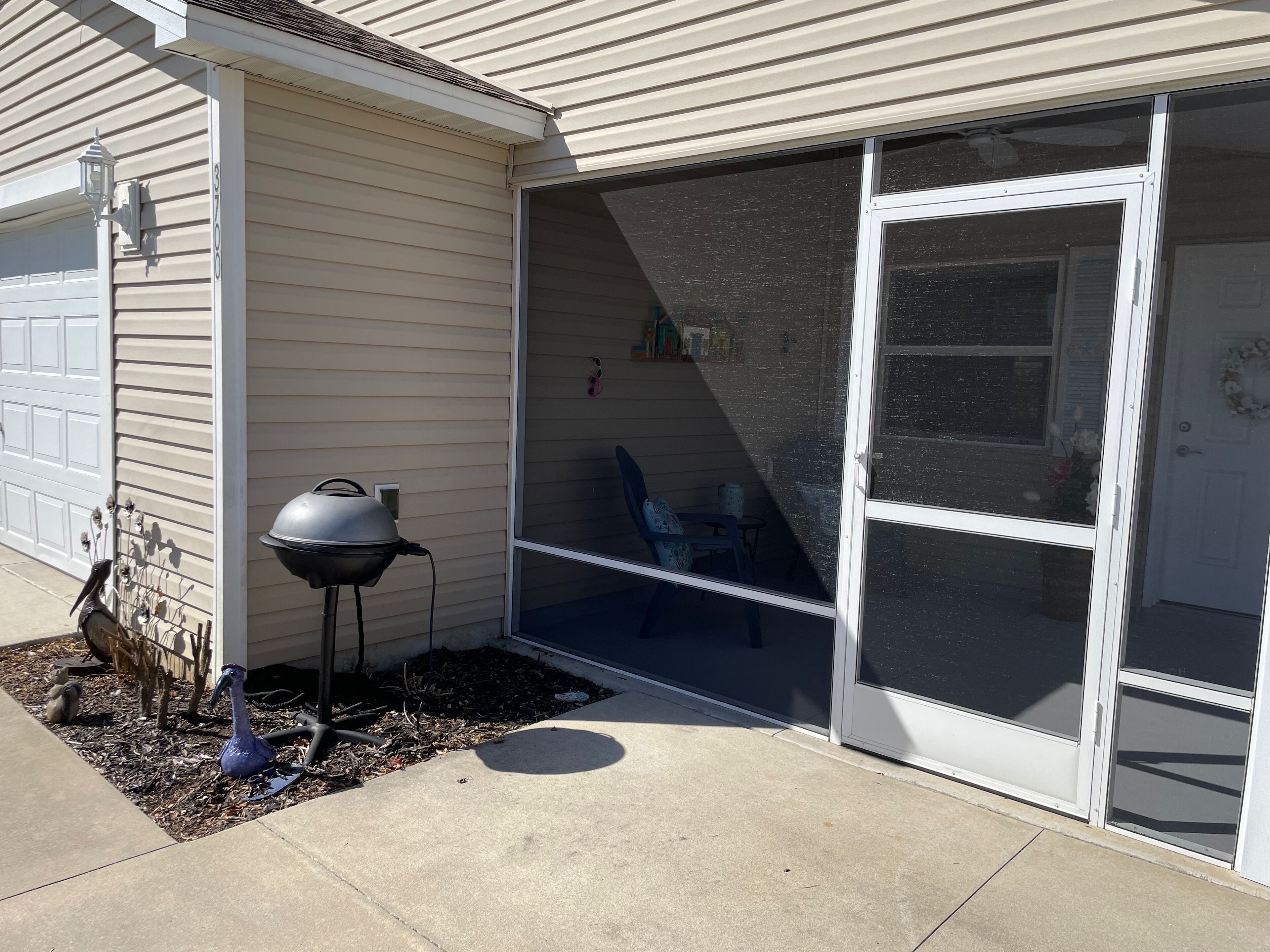 A garage with a sliding glass door, a barbecue grill, and a bird sculpture.