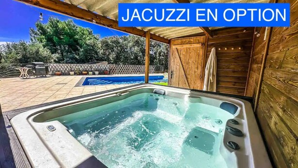 Un bain à remous avec une terrasse en bois et une piscine en arrière-plan.