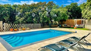 Une piscine rectangulaire à l’eau d’un bleu limpide, entourée d’une clôture en bois et d’une terrasse en bois.