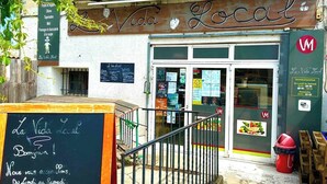 Une devanture de magasin avec une enseigne indiquant « La Vida Local » et un tableau noir où sont écrits des messages de bienvenue et les heures d’ouverture.