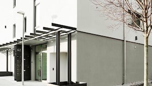 Ein modernes Gebäude mit Glastür, schwarzem Eingang und einer Treppe, die zu einer oberen Ebene führt.
