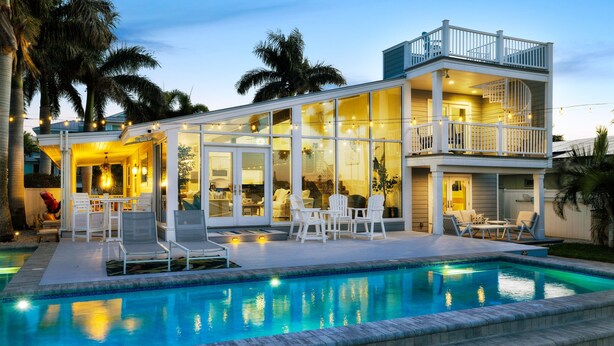 A two-story house with a swimming pool, outdoor furniture, and a balcony.