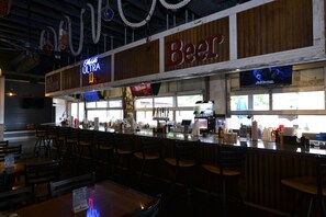Eine Bar mit einer Neonreklame für 'Ultra Beer' und einem Fernsehbildschirm, der einen Bären zeigt.
