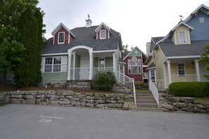 A row of houses with a stone wall in the foreground, a clear sky, and a street with a reserved parking sign. - Huge 4-bedroom cottage at Stormy Point. Near attractions. Family Friendly. (Branson)