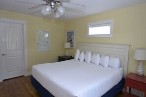 A hotel room with a bed, a nightstand, a lamp, a ceiling fan, a door, and a window. - Huge 4-bedroom cottage at Stormy Point. Near attractions. Family Friendly. (Branson)