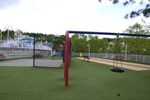 Ein Spielplatz mit Schaukel, Rutsche und einem eingezäunten Bereich.