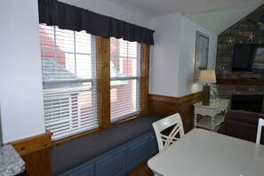 A room with a bench by a window, a table, chairs, a lamp, and a fireplace. - Huge 4-bedroom cottage at Stormy Point. Near attractions. Family Friendly. (Branson)