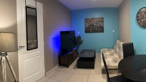 Una sala de estar con un sofá, una mesa de centro, un televisor y una lámpara.