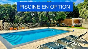 Una piscina con cubierta de madera, sillas de descanso y valla de madera.