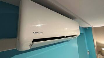 Un appareil de climatisation blanc, portant l’inscription « CoolSmart », est fixé sur un mur bleu.