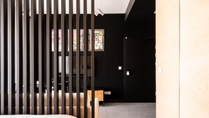 A modern room with a bed, a desk, and a chair. There is a black wall with a window and a door. - RentPlanet - Apartament Śrutowa (Wroclaw)