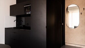 A modern kitchen with dark cabinetry, a black countertop, and a built-in oven. - RentPlanet - Apartament Śrutowa (Wroclaw)