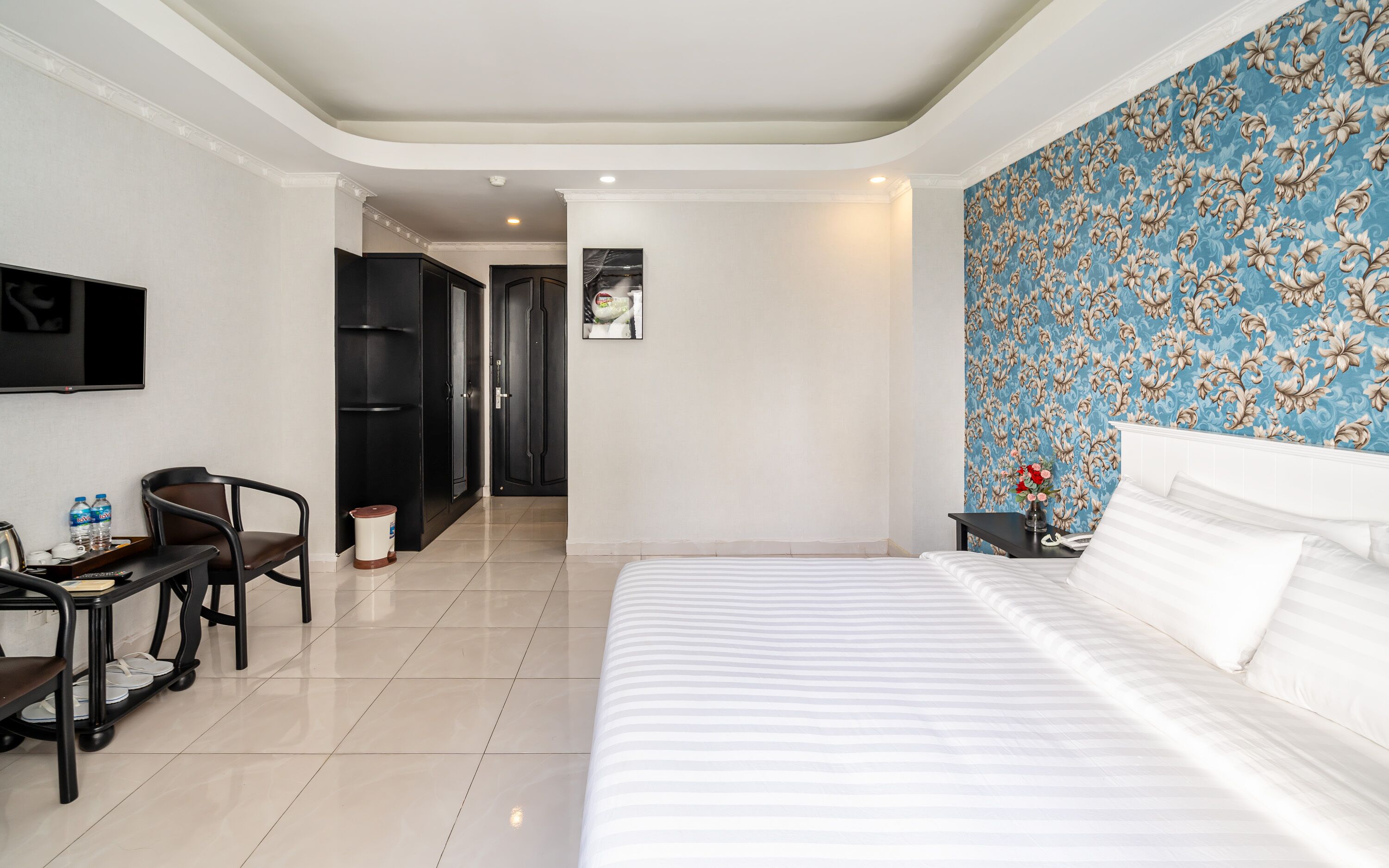 Une chambre d’hôtel comprenant un lit, un bureau avec une chaise, une télévision et une salle de bain avec douche.