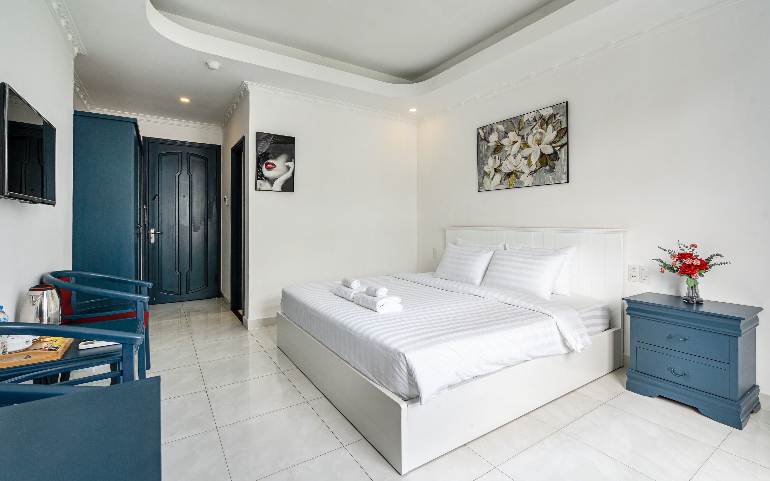 A modern bedroom with a bed, a nightstand, a desk, and a chair.