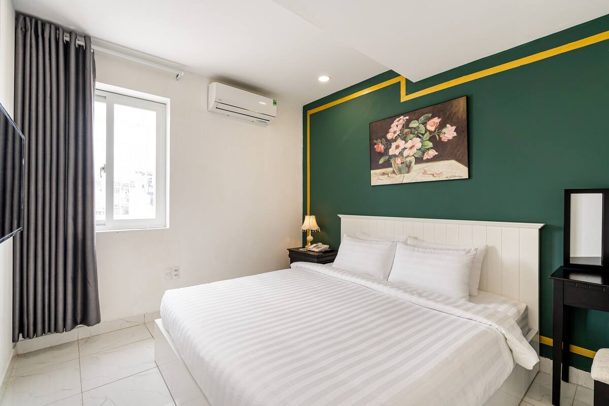 Une chambre d’hôtel avec un lit, une table de chevet, un tableau et un appareil de climatisation.