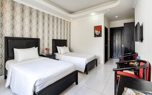 A hotel room with two beds, a small table with a vase, a painting on the wall, and a TV mounted on the wall. - La Casona Boutique Hotel (Ho Chi Minh City)