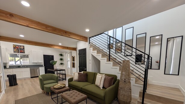Un salon moderne avec un canapé vert, une table basse et un escalier.