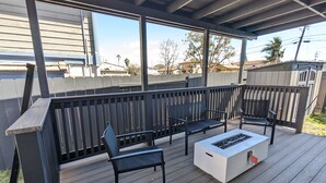 Une terrasse extérieure avec un foyer, deux chaises et un banc.