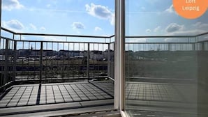 Een balkon met een metalen hekwerk, een uitzicht op de lucht en een verafgelegen landschap.