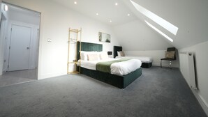 Ein Schlafzimmer mit einem großen Bett, einem Sessel, einem Schreibtisch und einem Oberlicht.