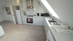 Eine moderne Küche mit weißen Schränken, einem eingebauten Backofen, einer Mikrowelle und einer Kaffeemaschine.