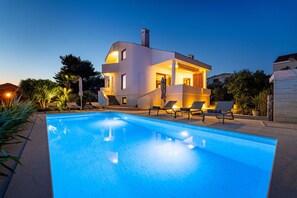 A modern two-story house with a swimming pool, lounge chairs, and a well-lit outdoor area. - Villa Bruna (Zadar)