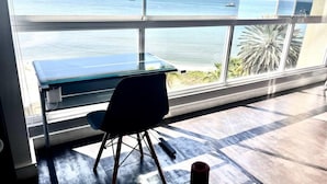 Una stanza con una scrivania e una sedia rivolte verso una grande finestra con vista sull'oceano.