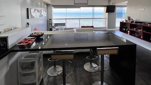 Una cucina moderna con isola centrale, sgabelli da bar e vista sull'oceano.