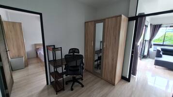 Een moderne kamer met een houten vloer, een zwarte bureaustoel, een houten garderobe en een grote spiegel.