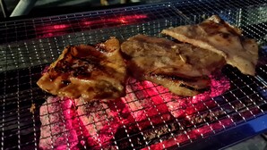 A grill with two pieces of meat cooking over glowing coals. - D&A Paradise Villas (Koh Samui)