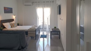 A hotel room with a bed, a sofa, a small table, a TV, and a balcony with a view. - City O-Central (Athens)