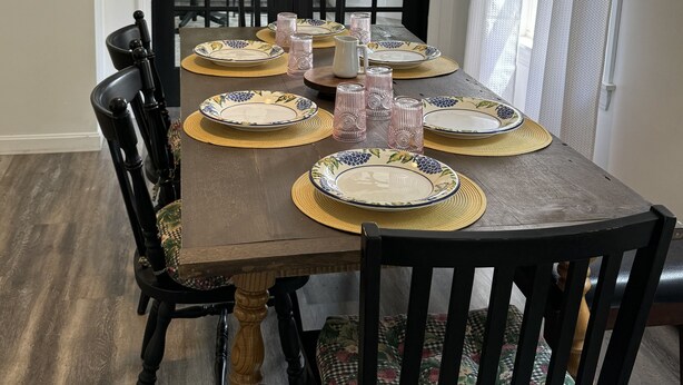A dining table set for six with placemats, plates, and glasses, in front of a door labeled "FARMER'S MARKET". - The Modern Maine Retreat (Oakland)