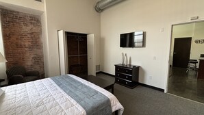 Ein Hotelzimmer mit Bett, Schreibtisch, Fernseher und Kleiderschrank.