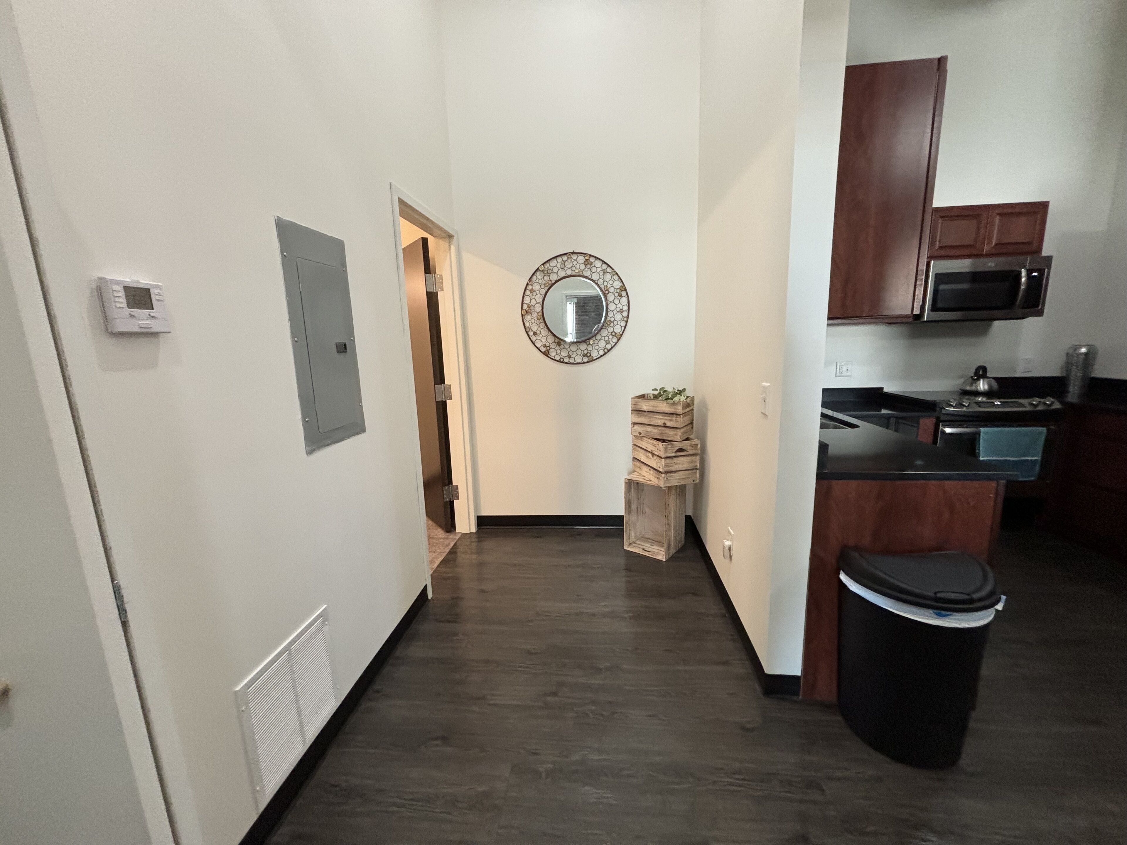 A modern kitchen with dark wood cabinets, a microwave, and a stove. There is a small wooden stool with a plant on top.