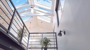 A high ceiling with skylights, a potted plant, and a wall-mounted light fixture. - Le Loft du pré (Le Pré-Saint-Gervais)