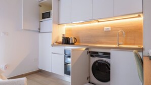 A compact kitchen with a built-in microwave, a sink, and a washing machine.