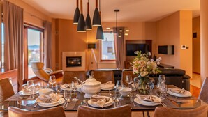 A dining area with a table set for four, including plates, glasses, and cutlery. There are chairs around the table, and a vase with flowers on the table.