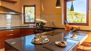 A modern kitchen with a central island, a coffee station, and a view of the outdoors.