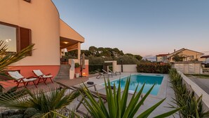 A modern house with a swimming pool, outdoor seating, and a well-maintained garden.