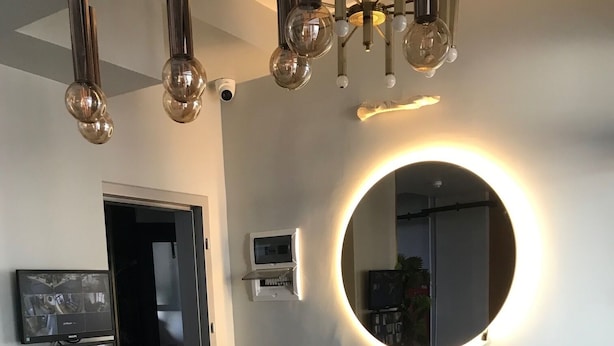 A reception desk with a modern design, a round mirror with a light halo, and a ceiling with spherical light fixtures. - My Life Otel (Istanbul)
