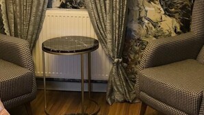 A room with a radiator, two patterned chairs, a small round table, and curtains with a floral design. - My Life Otel (Istanbul)